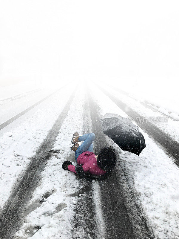 躺在路中间的女人，滑倒在新雪/冰上